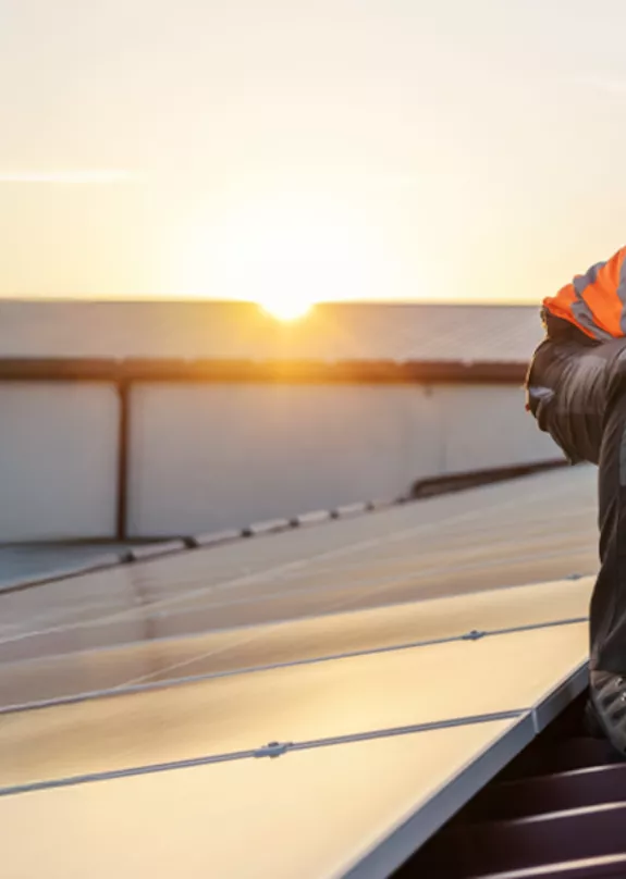 Man on rooftop installing solar panels